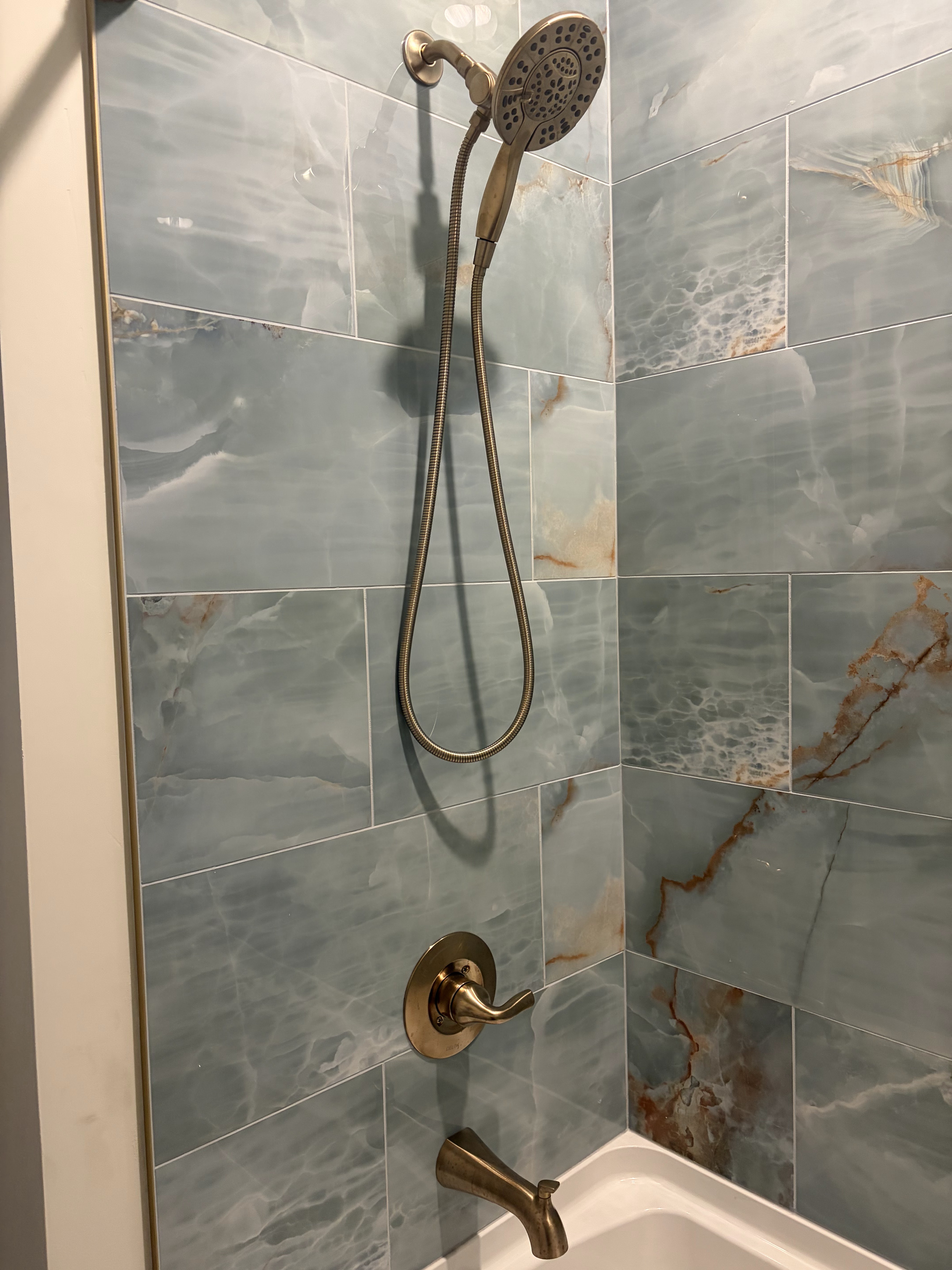 Marble-look tiled shower with bronze fixtures